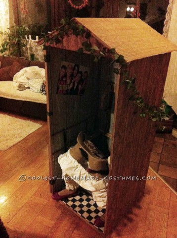 Ilusión divertida del traje: una mujer bávara tradicional que se sienta en un retrete de madera